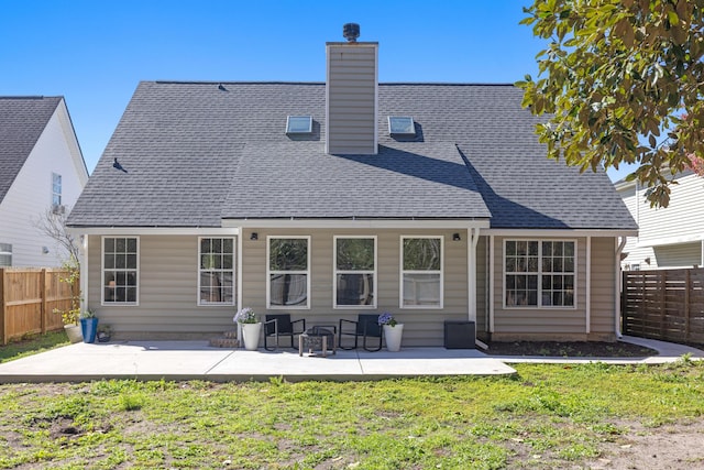 back of house featuring fence private yard, roof with shingles, a chimney, and a patio