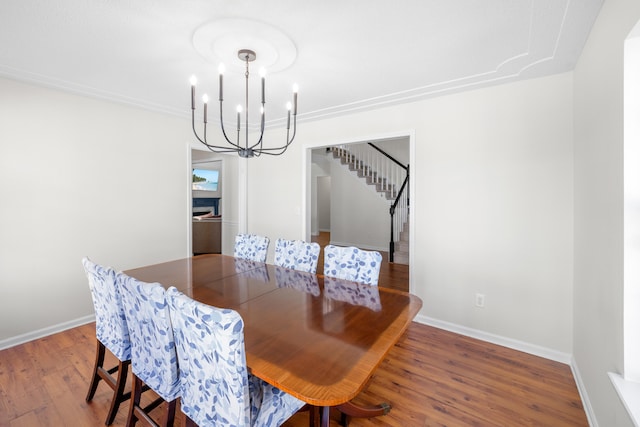 dining space with an inviting chandelier, baseboards, stairway, and wood finished floors