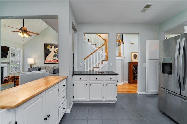kitchen with a ceiling fan, visible vents, a peninsula, stainless steel fridge with ice dispenser, and white cabinets