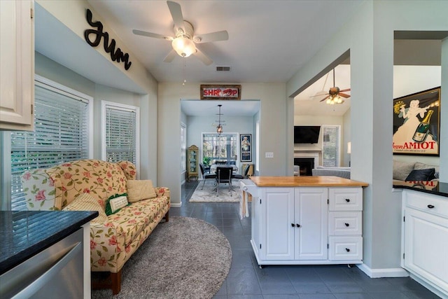 kitchen featuring visible vents, plenty of natural light, white cabinets, a fireplace, and ceiling fan