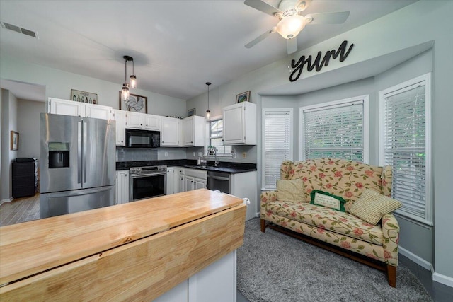 kitchen featuring visible vents, decorative light fixtures, stainless steel appliances, white cabinetry, and a sink