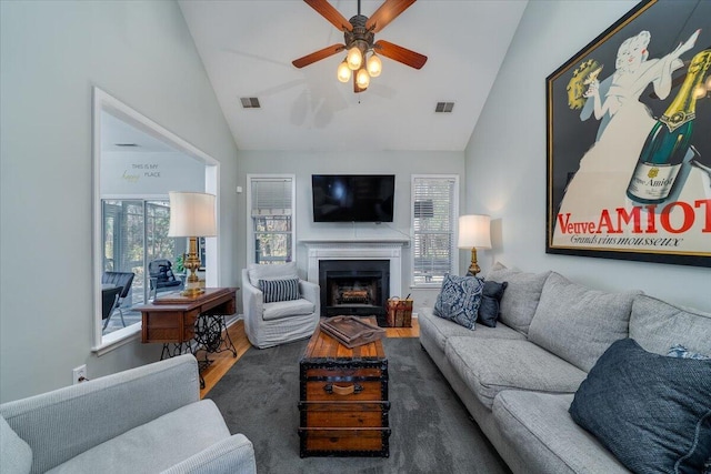 living room featuring visible vents, wood finished floors, a ceiling fan, and vaulted ceiling