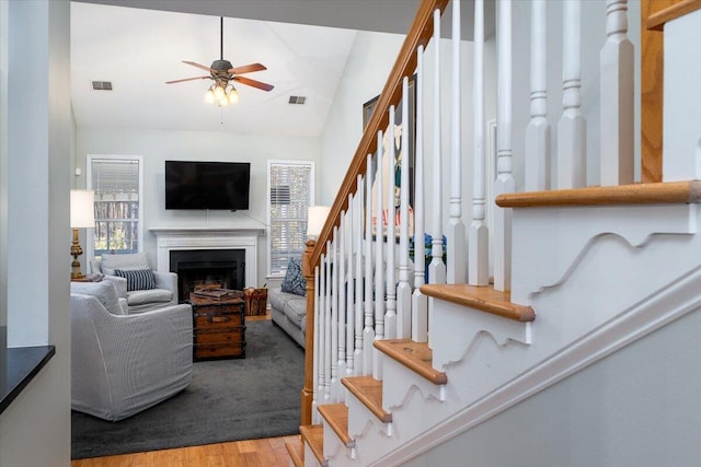 living room featuring stairway, a ceiling fan, visible vents, a fireplace, and light wood-type flooring