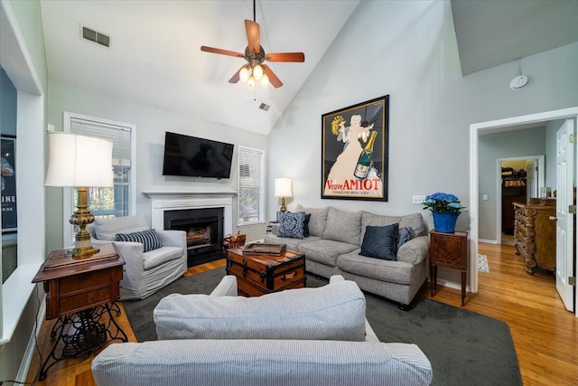 living room featuring a wealth of natural light, visible vents, wood finished floors, and a ceiling fan