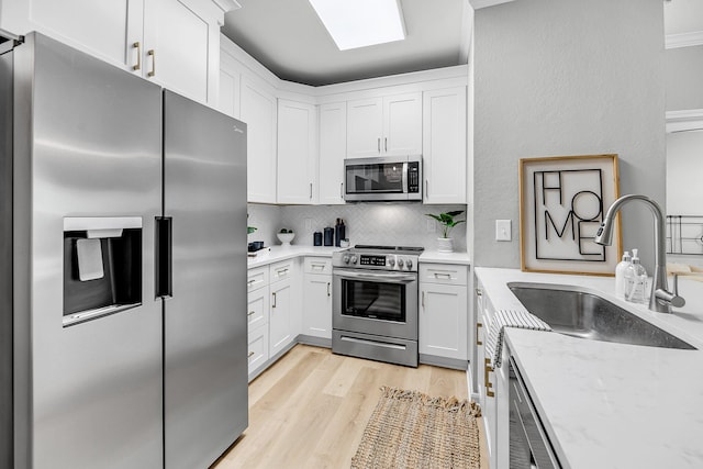 60 Fenwick Hall Aly Unit 415, Johns Island, SC 29455 - kitchen with appliances with stainless steel finishes, a sink, backsplash, white cabinetry, and light wood-style flooring