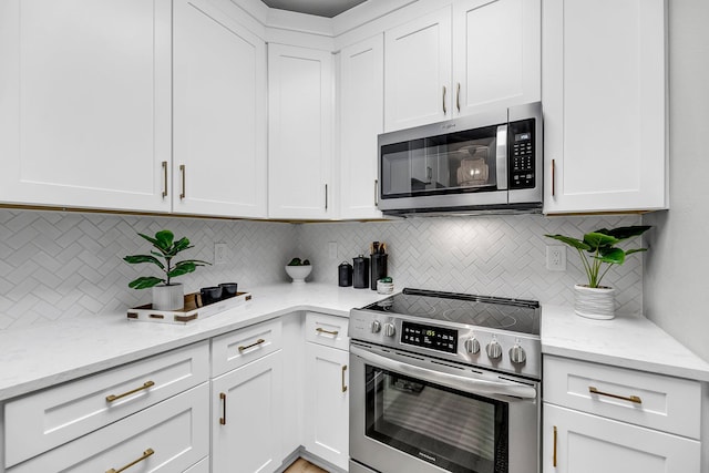 60 Fenwick Hall Aly Unit 415, Johns Island, SC 29455 - kitchen featuring appliances with stainless steel finishes, tasteful backsplash, white cabinets, and light stone counters