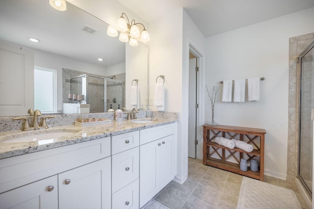 full bathroom with a shower stall, double vanity, and tile patterned floors
