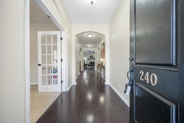 interior space featuring arched walkways, dark wood-style flooring, and baseboards