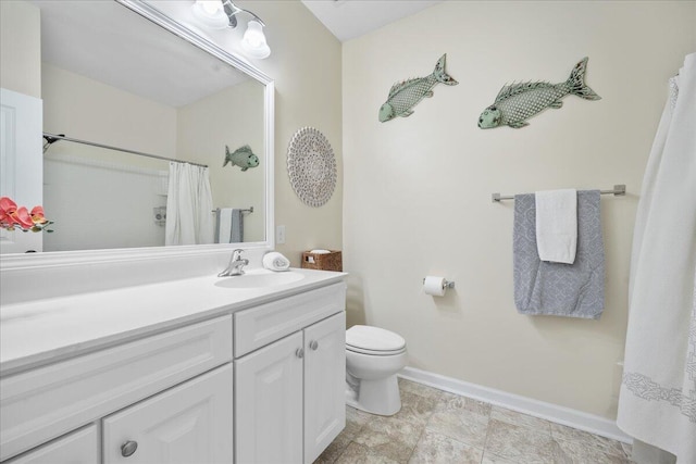 bathroom featuring toilet, baseboards, and vanity