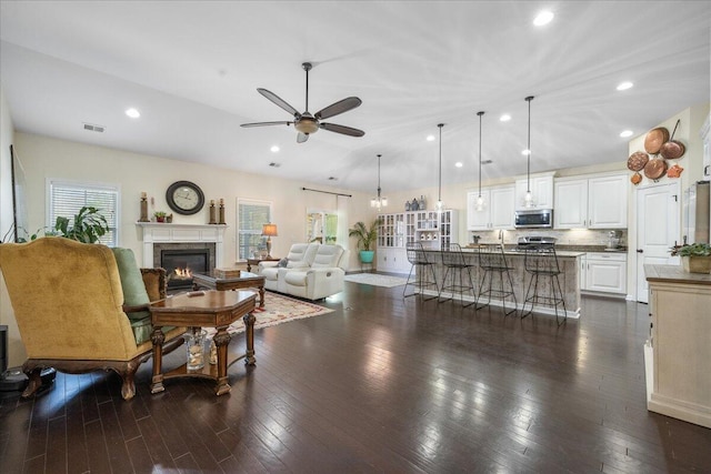 living room with a ceiling fan, vaulted ceiling, dark wood finished floors, and a high end fireplace