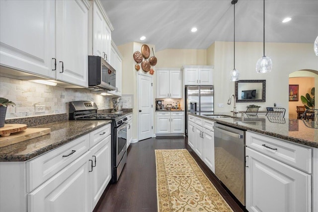 kitchen featuring arched walkways, a sink, white cabinetry, appliances with stainless steel finishes, and dark wood finished floors