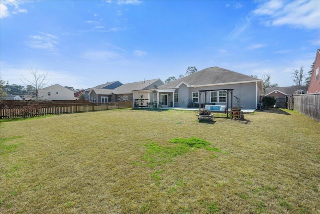 back of house with an outdoor fire pit, a fenced backyard, and a yard