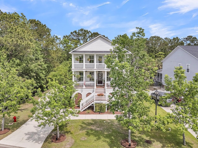 neoclassical / greek revival house featuring stairs, a balcony, covered porch, and a front yard