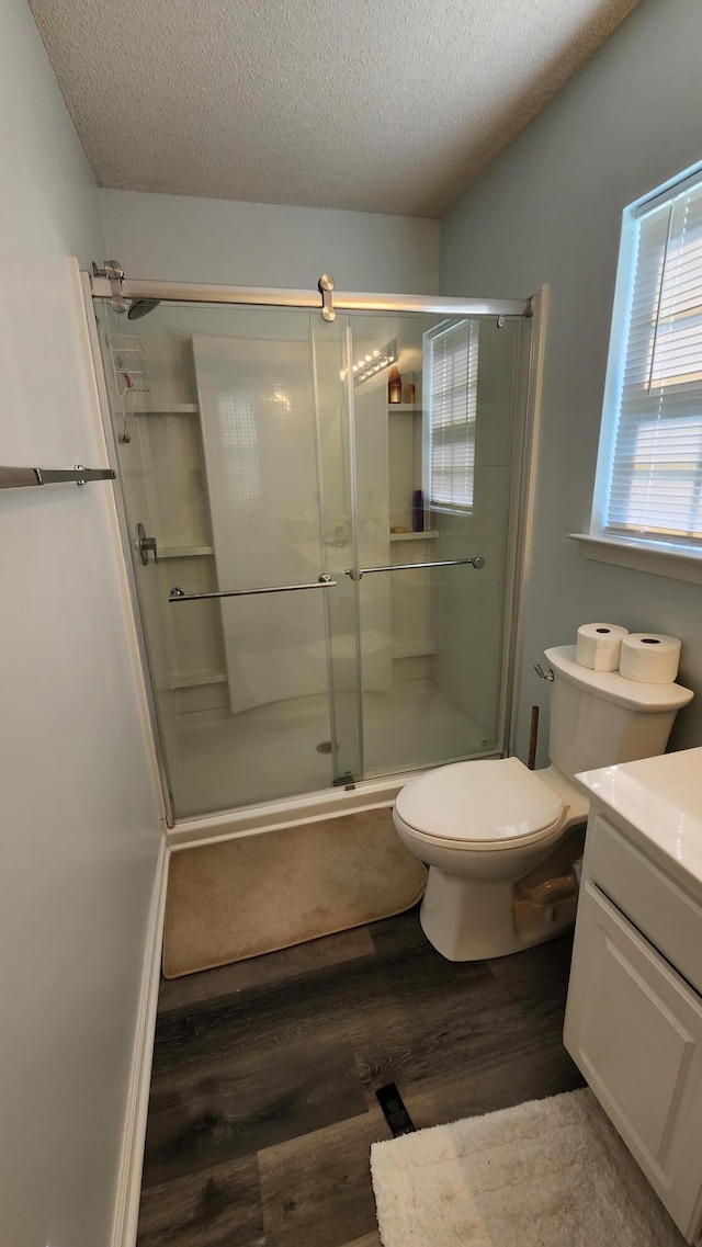 bathroom featuring hardwood / wood-style floors, vanity, toilet, a textured ceiling, and an enclosed shower