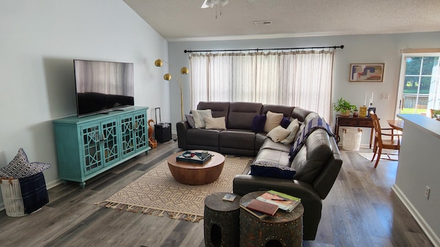 living room with a textured ceiling, ceiling fan, and dark wood-type flooring