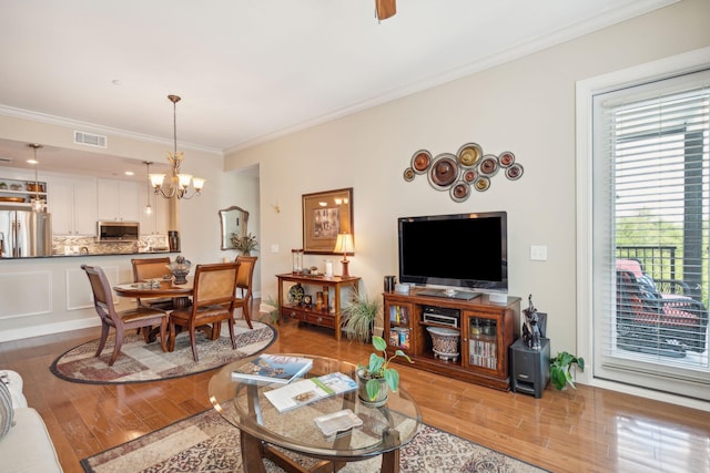 living room with visible vents, crown molding, and wood finished floors