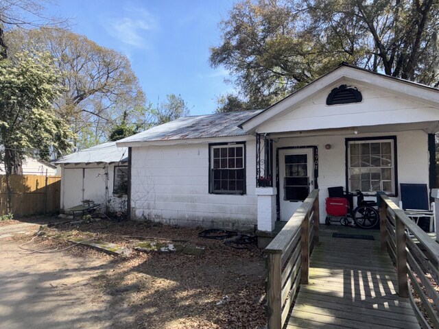 1907 Helm Ave, North Charleston, SC 29405 - view of front of property with fence, a porch, concrete block siding, metal roof, and an outbuilding