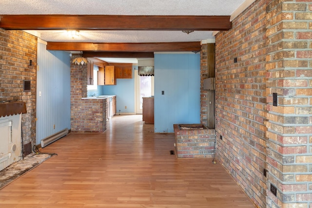 unfurnished living room with light wood-style floors, baseboard heating, a textured ceiling, and beamed ceiling