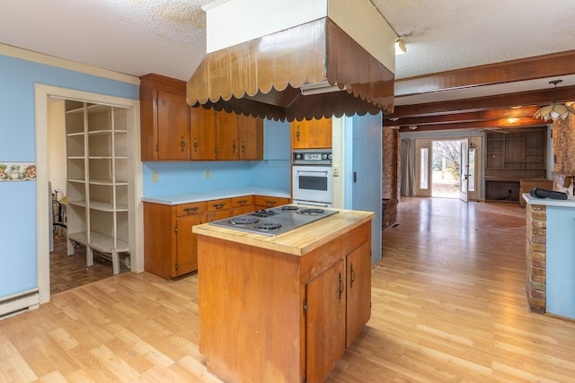 kitchen with light wood-style floors, white oven, stainless steel gas cooktop, and a textured ceiling