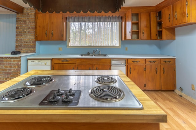 kitchen featuring white dishwasher, light countertops, light wood-style floors, gas cooktop, and a sink