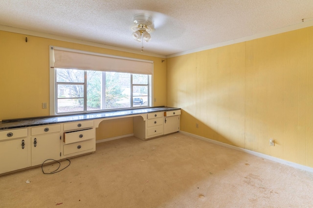 unfurnished office with built in study area, crown molding, light carpet, and a textured ceiling