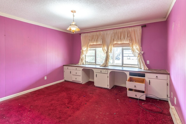 unfurnished office featuring crown molding, a textured ceiling, dark carpet, and built in desk