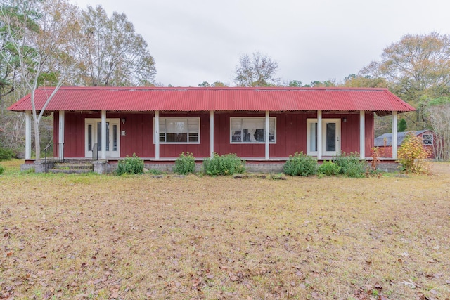 ranch-style home featuring covered porch, a front lawn, and board and batten siding