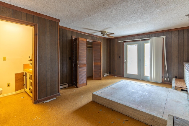 bedroom featuring wood walls, baseboard heating, and a textured ceiling