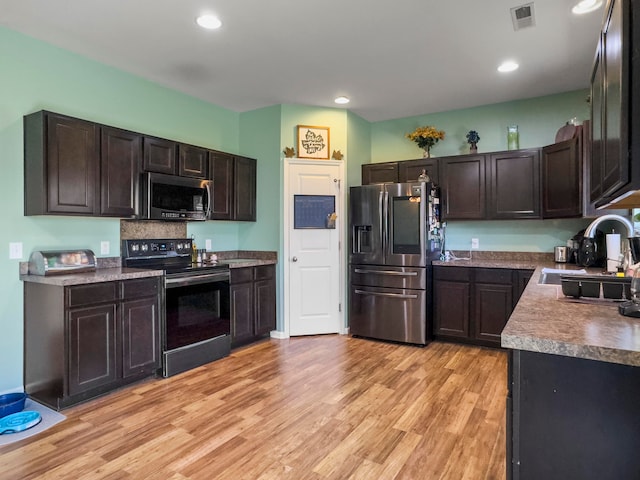 kitchen featuring appliances with stainless steel finishes, sink, dark brown cabinets, and light wood-type flooring