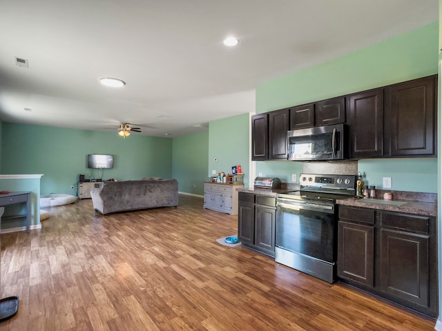 kitchen with dark brown cabinets, stainless steel appliances, and light wood-type flooring