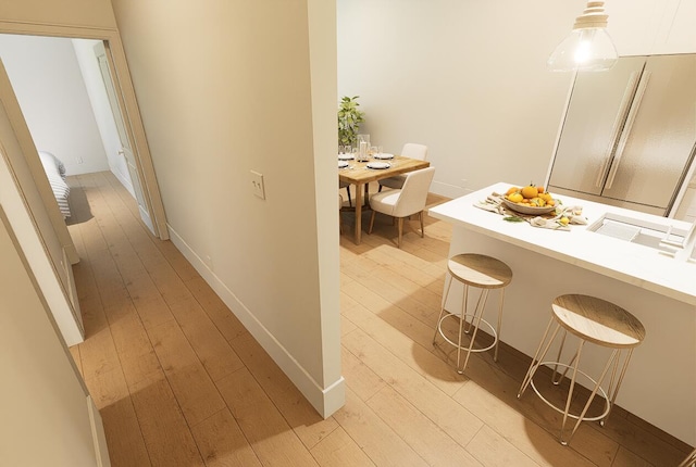 hall featuring light wood-style flooring and baseboards