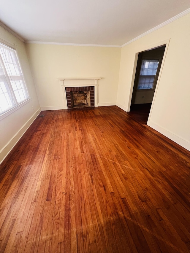 unfurnished living room featuring a brick fireplace, ornamental molding, and dark hardwood / wood-style floors