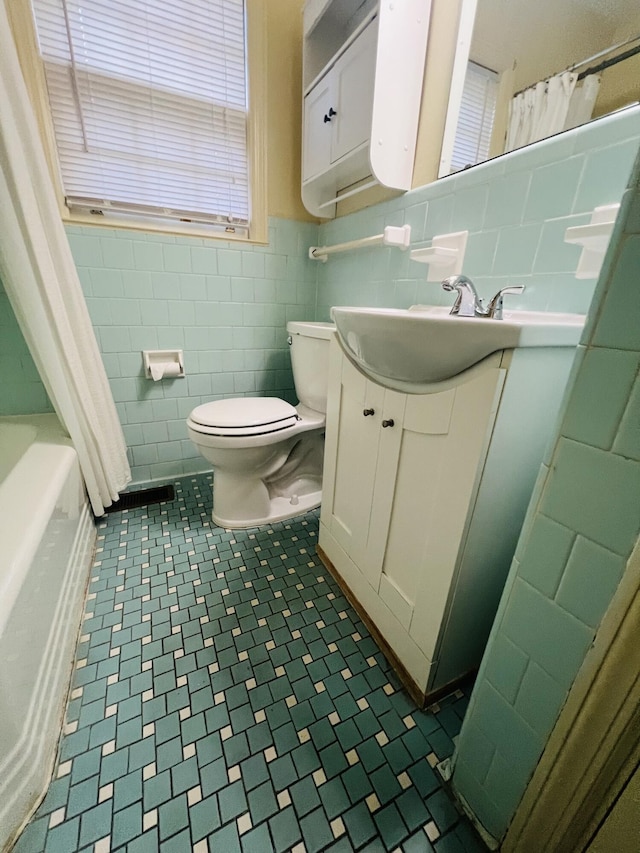 bathroom featuring vanity, toilet, and tile walls