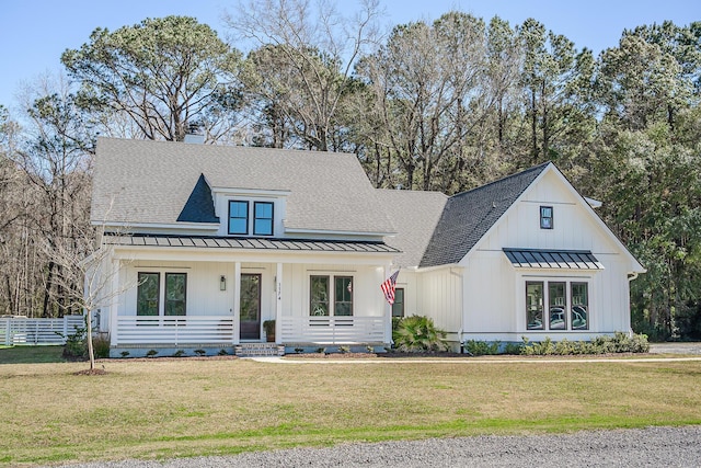 modern farmhouse with board and batten siding, a front lawn, a standing seam roof, and fence