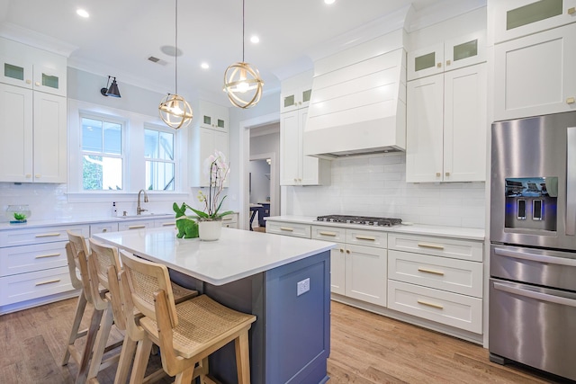 kitchen featuring a center island, light wood-type flooring, light countertops, appliances with stainless steel finishes, and a sink