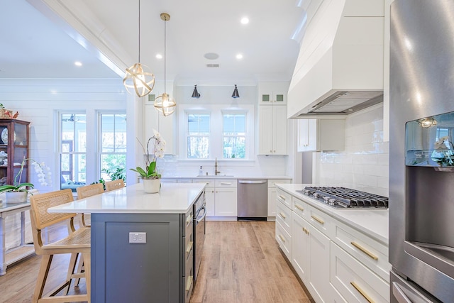 kitchen featuring a kitchen breakfast bar, white cabinets, light countertops, and stainless steel appliances