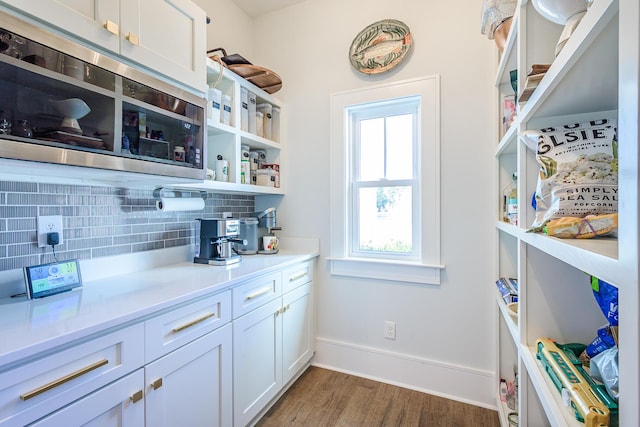 kitchen featuring tasteful backsplash, stainless steel microwave, wood finished floors, white cabinets, and open shelves