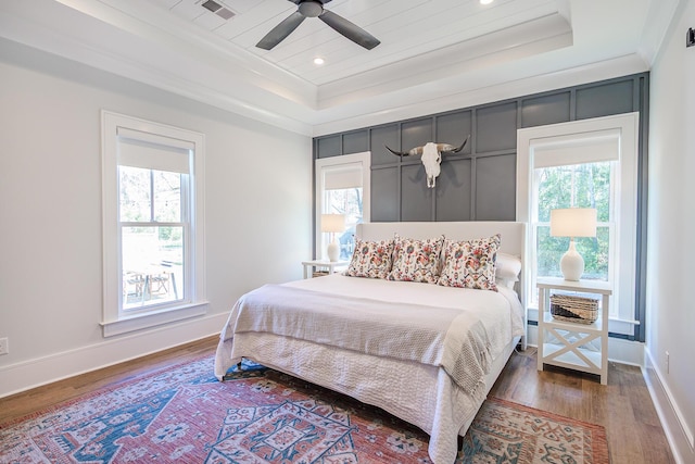 bedroom with multiple windows, a raised ceiling, and wood finished floors