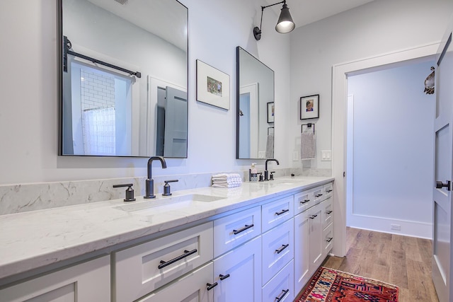 full bath with double vanity, wood finished floors, and a sink