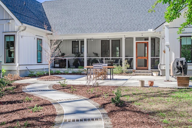 back of property with a patio area, a shingled roof, and a sunroom