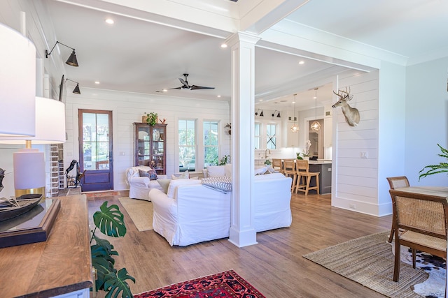 living room with a wealth of natural light, wood finished floors, crown molding, and ceiling fan