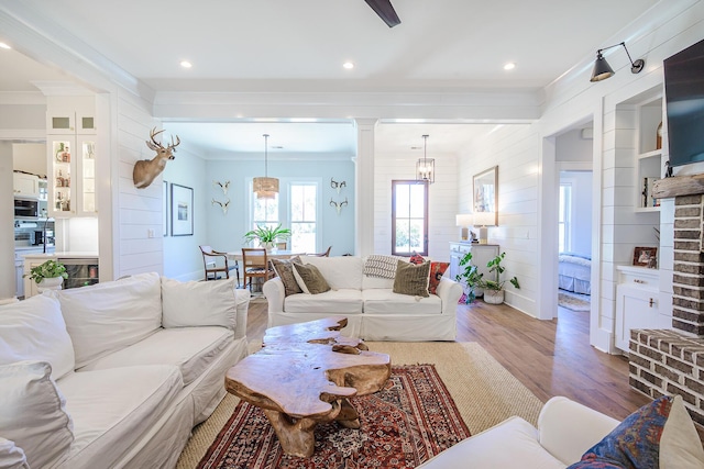 living room with recessed lighting, decorative columns, wood finished floors, and ornamental molding