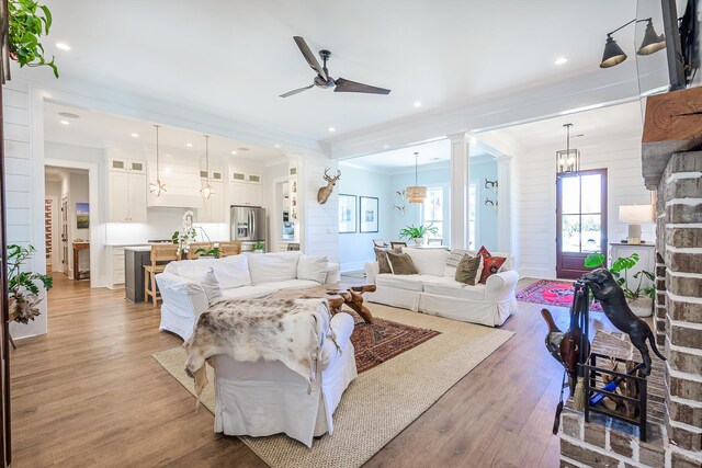 living area with light wood finished floors, ceiling fan, ornamental molding, recessed lighting, and ornate columns