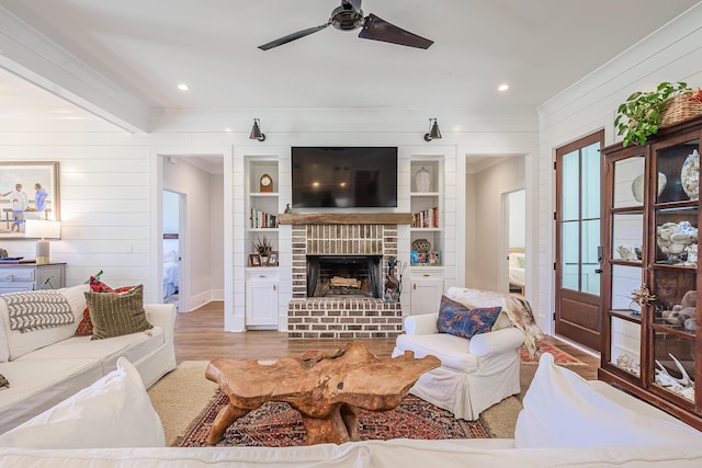 living room featuring wood finished floors, a ceiling fan, recessed lighting, ornamental molding, and a brick fireplace