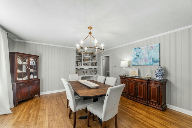 dining room featuring a notable chandelier, light wood-type flooring, and crown molding