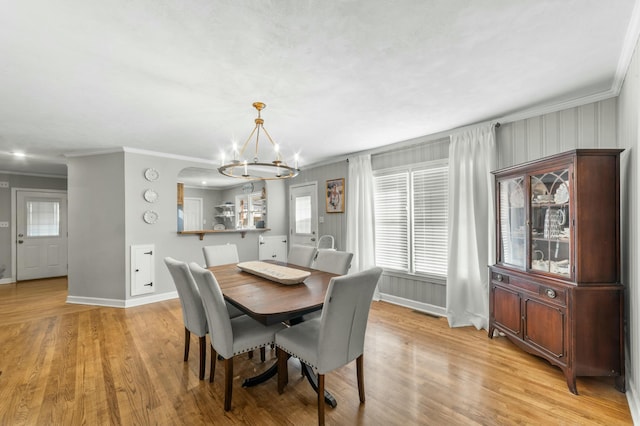 dining space featuring light wood-type flooring, crown molding, and a chandelier