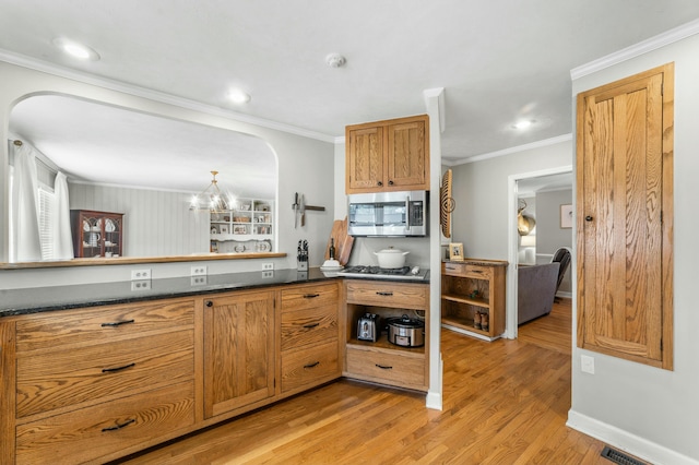 kitchen featuring crown molding, light hardwood / wood-style flooring, appliances with stainless steel finishes, kitchen peninsula, and a chandelier