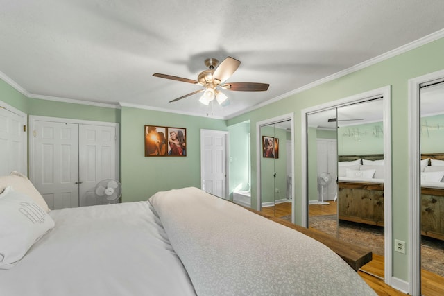 bedroom featuring hardwood / wood-style floors, two closets, ceiling fan, and ornamental molding