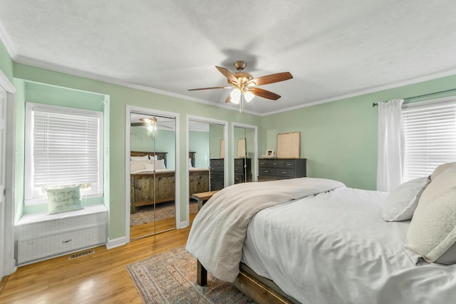 bedroom featuring ornamental molding, multiple windows, and two closets