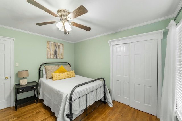 bedroom featuring ceiling fan, light hardwood / wood-style floors, ornamental molding, and a closet